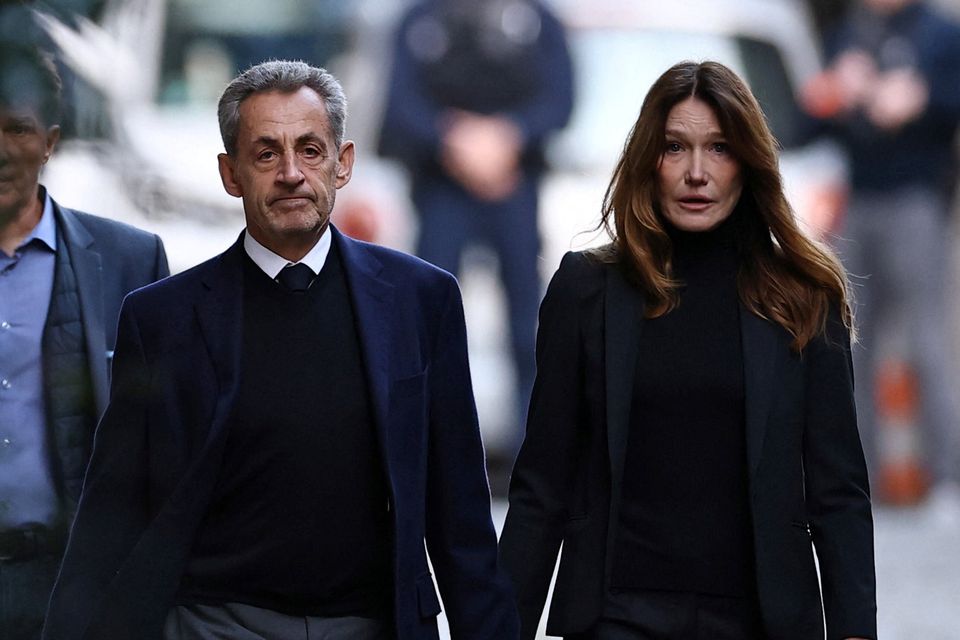 Carla Bruni holds hands with her husband Nicholas Sarkozy on the first day of his incarceration. Photo: Reuters
